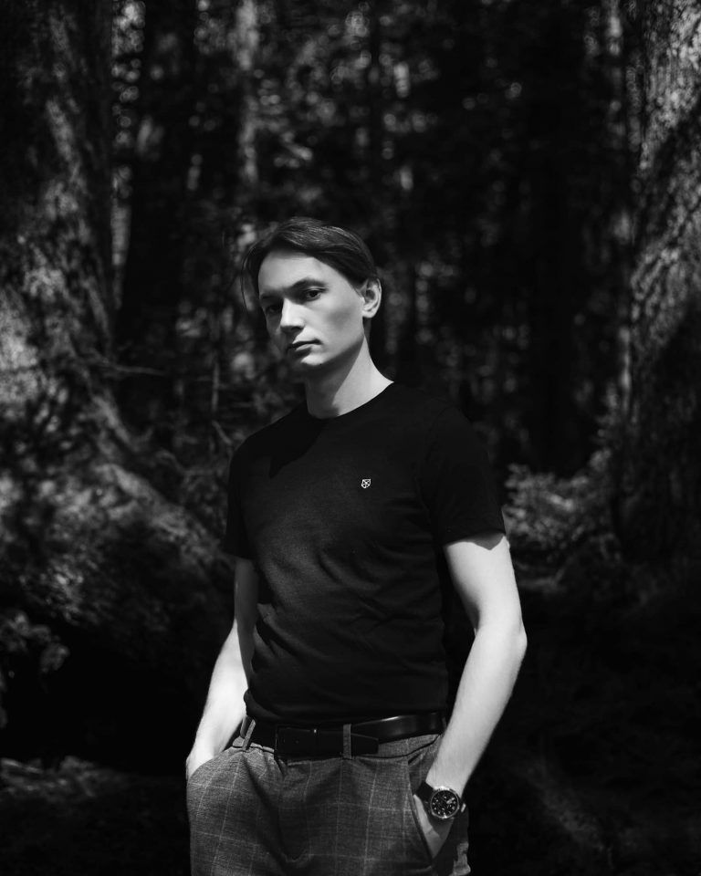 Schwarz-weiß Portrait eines Mannes im Wald mit ernstem Blick, Natur Fotoshooting Vorarlberg.
