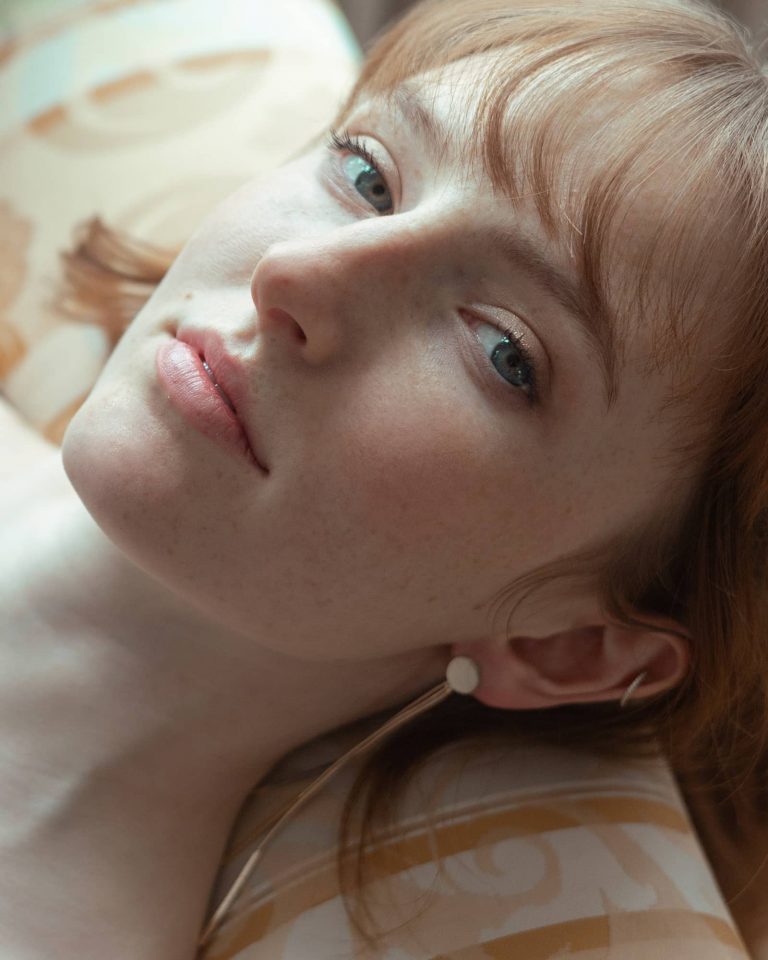 Liegendes Portrait einer Frau mit Sommersprossen und natürlichem Licht, Fine Art Fotoshooting.