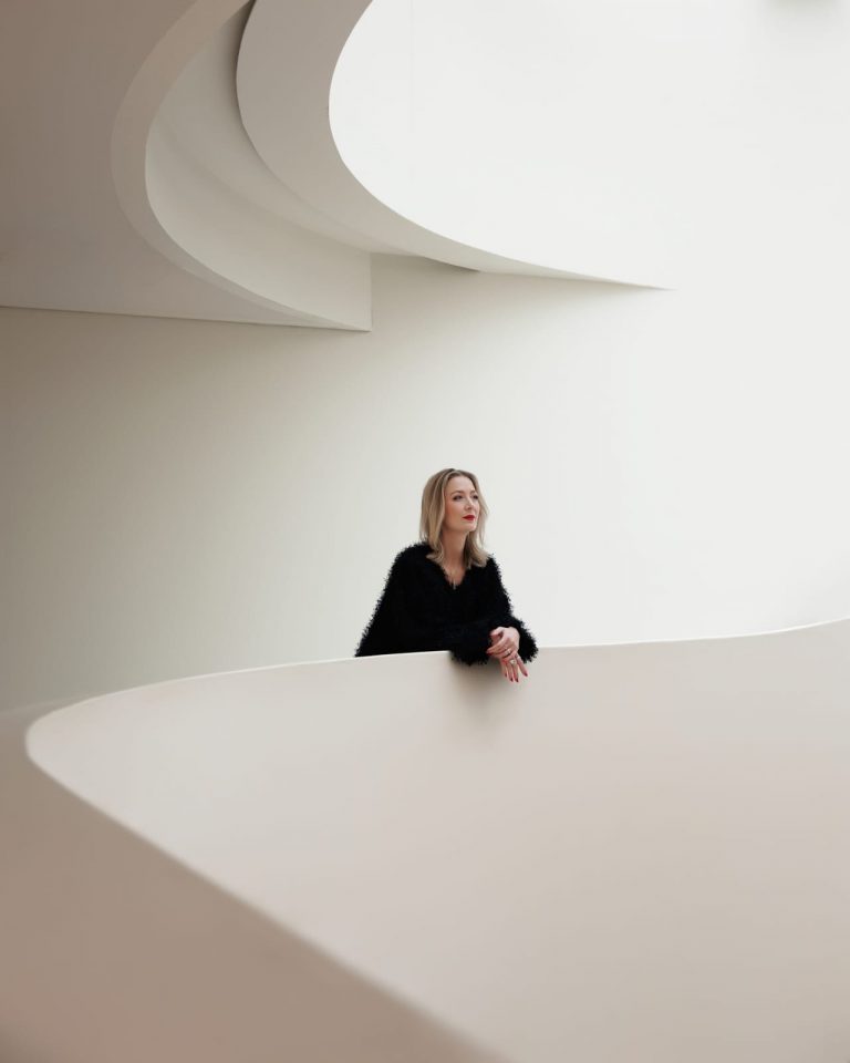 Minimalistisches Architekturportrait einer Frau im schwarzen Outfit, modernes Business-Fotoshooting.