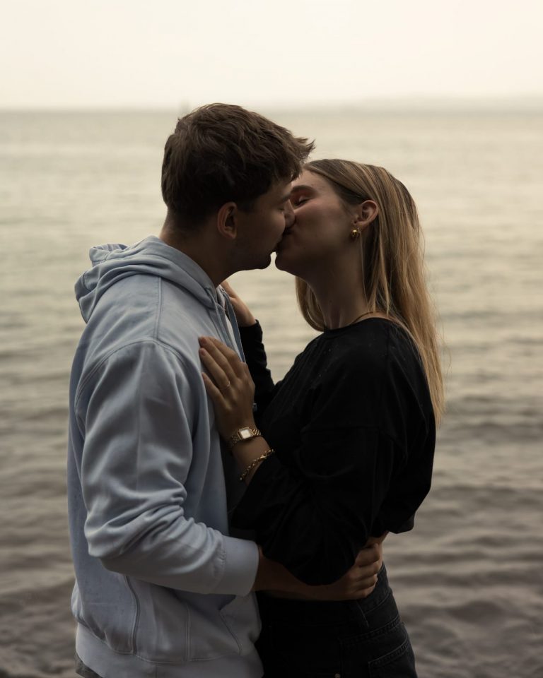 Emotionaler Kuss während eines Paarfotoshootings in natürlicher Umgebung.