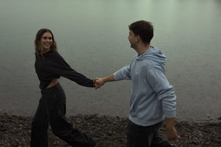 Paarshooting am See bei Regenwetter – authentischer Moment voller Freude.