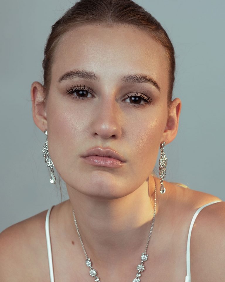 Nahaufnahme eines weiblichen Models mit natürlichen Gesichtszügen, dezentem Make-up und funkelndem Schmuck. Model Shooting, Model Fotoshooting Vorarlberg, Sedcardshooting Vorarlberg, Sedcardfotos.