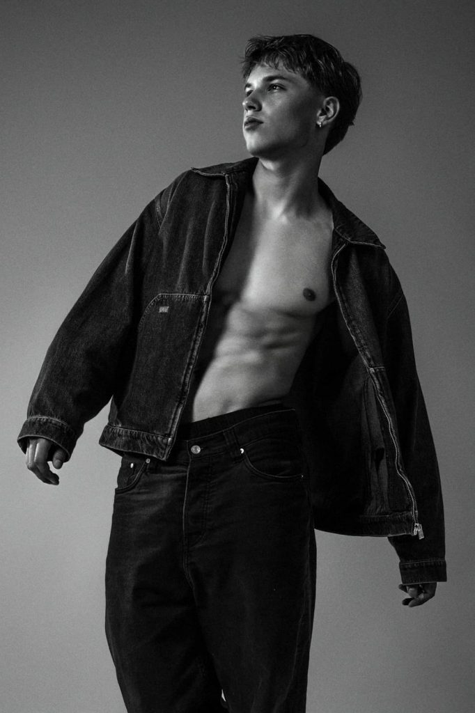 Männliches Model in Schwarz-Weiß beim Sedcardshooting Vorarlberg, mit offener Jeansjacke und Blick in die Ferne – Model Fotoshooting für Sedcardfotos.