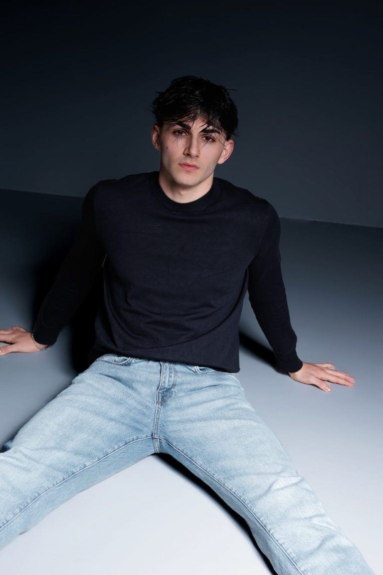 Männliches Model in Jeans und schwarzem Pullover sitzt auf dem Boden – Sedcardshooting Vorarlberg