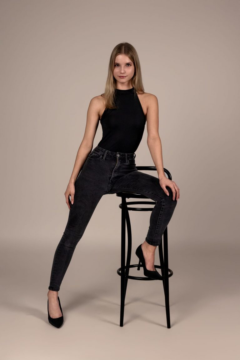 Model in schwarzem Top und Jeans posiert auf Stuhl – Sedcardshooting für Modelkartei in Vorarlberg
