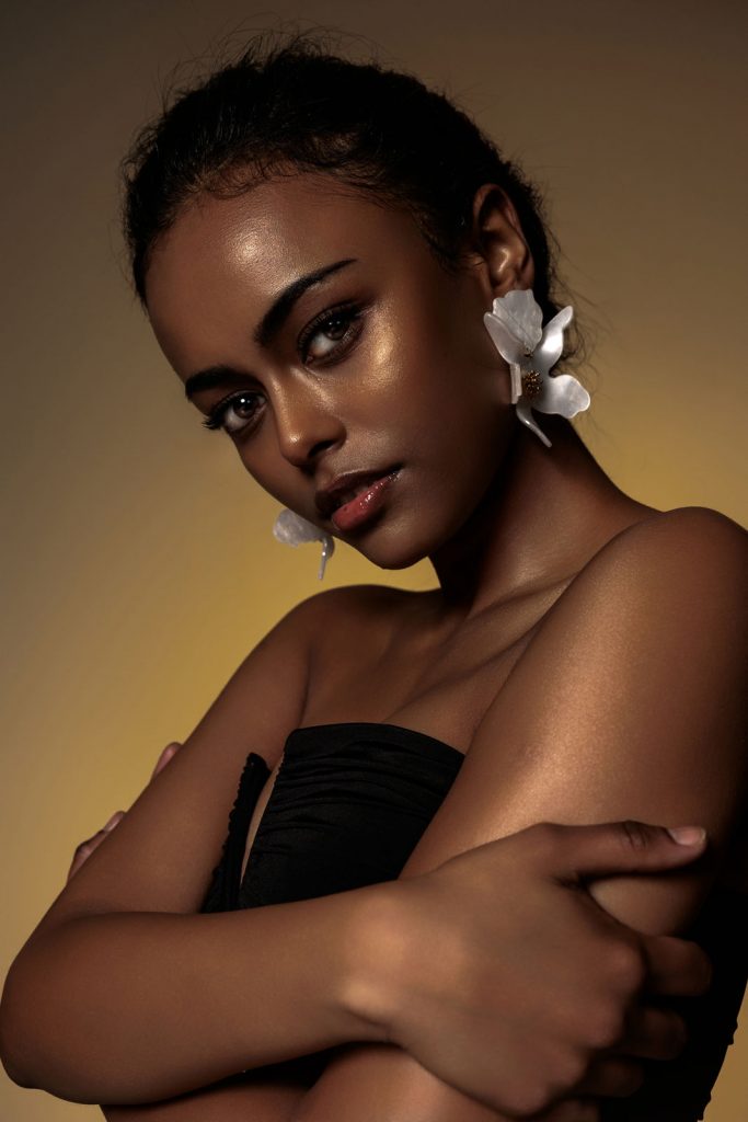 Foto von Frau mit großen Ohrringen, gelber Studiohintergrund, Beauty Portrait Vorarlberg.